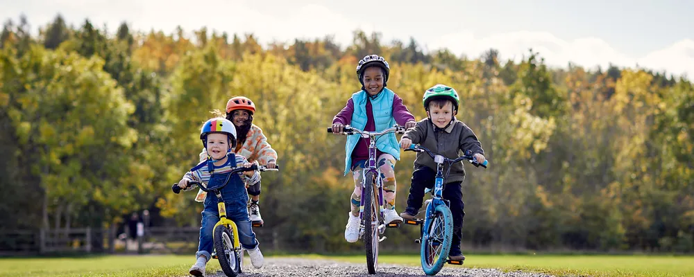 4 kids riding bikes of different sizes on an autumn day