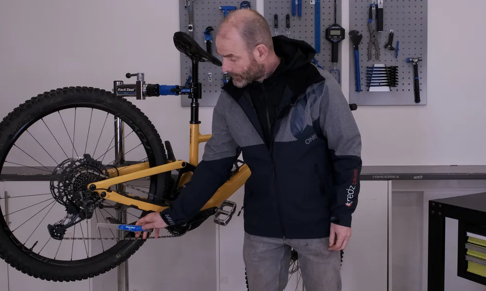 Mechanic checking chain wear with park tool chain wear checker