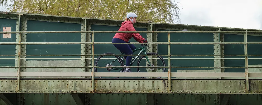 a hybrid sports bike is ridden across a bridge