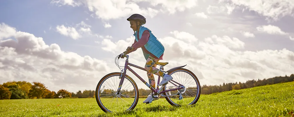 Girl riding a 26" wheel junior bike in the park on a summer day