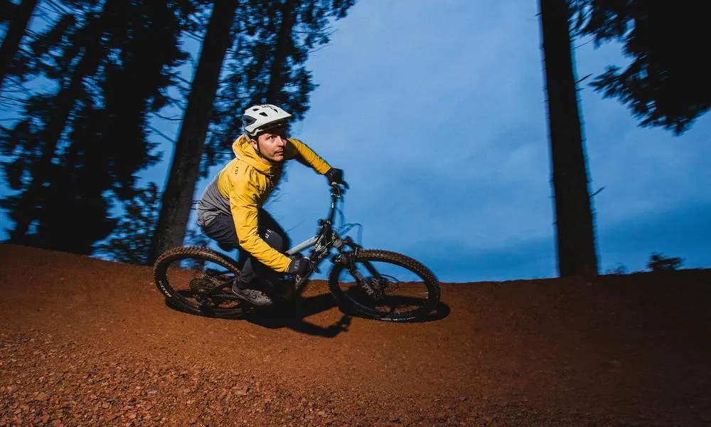 riding a mountain bike round a berm in the evening