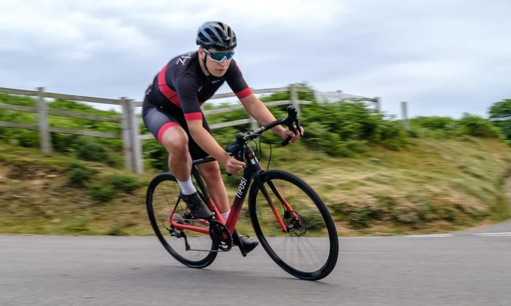 a road bike rides past, cables are visible