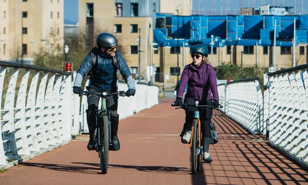 Two cyclists riding across a footbridge