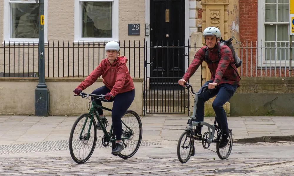 Two cyclists riding along a cobbled street