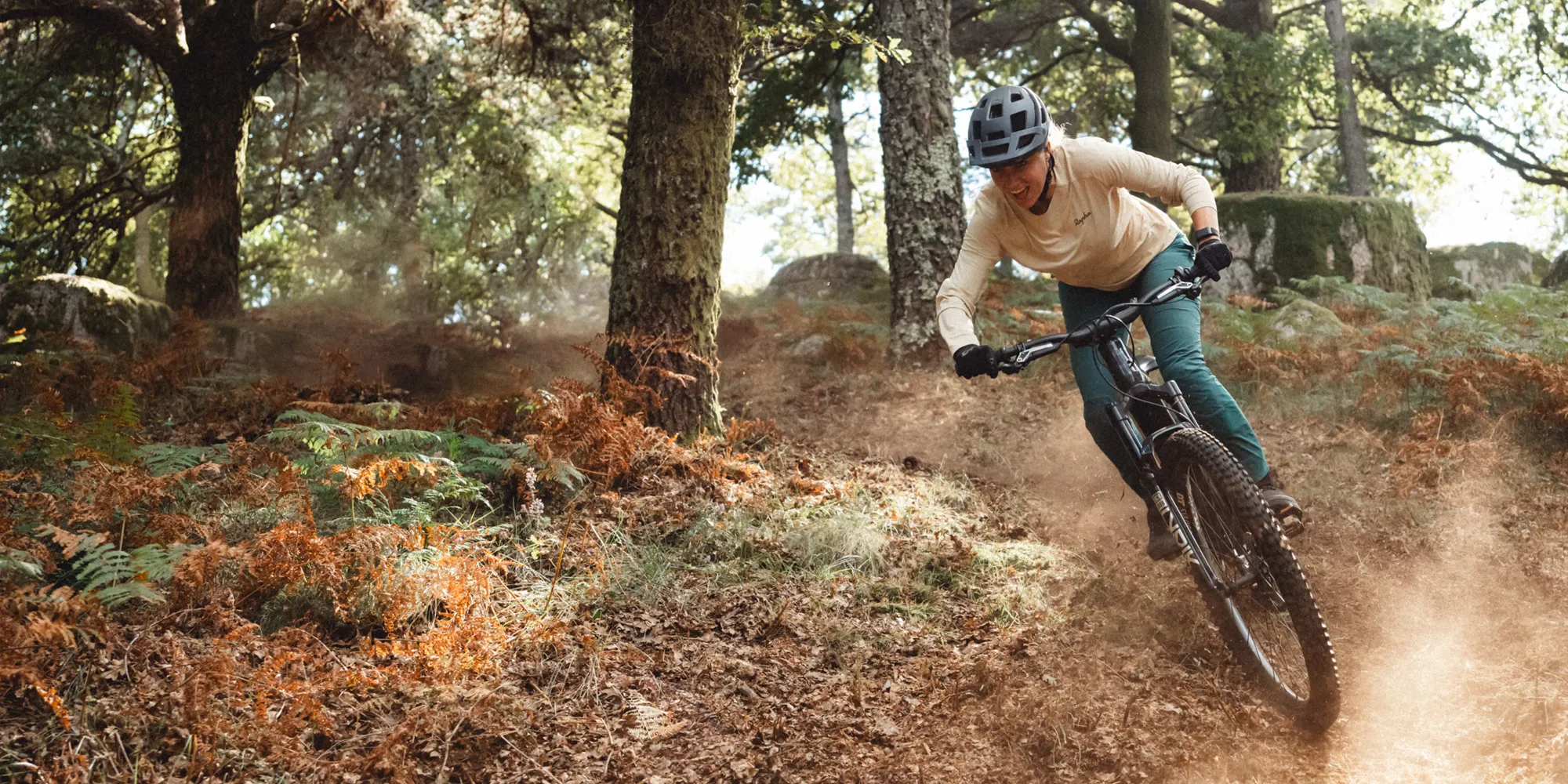 A mountain biker riding a Cannondale Moterra eMTB on a dusty trail