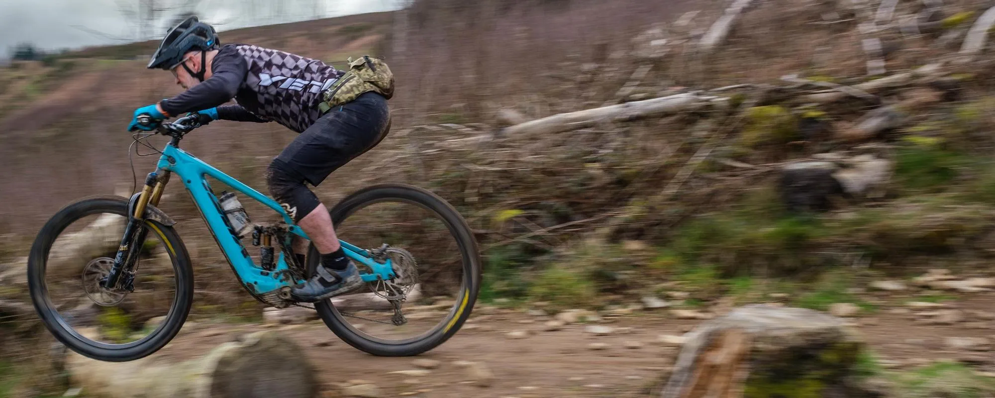 a yeti mountain bike is ridden off a drop, the rider is wearing a camelbak