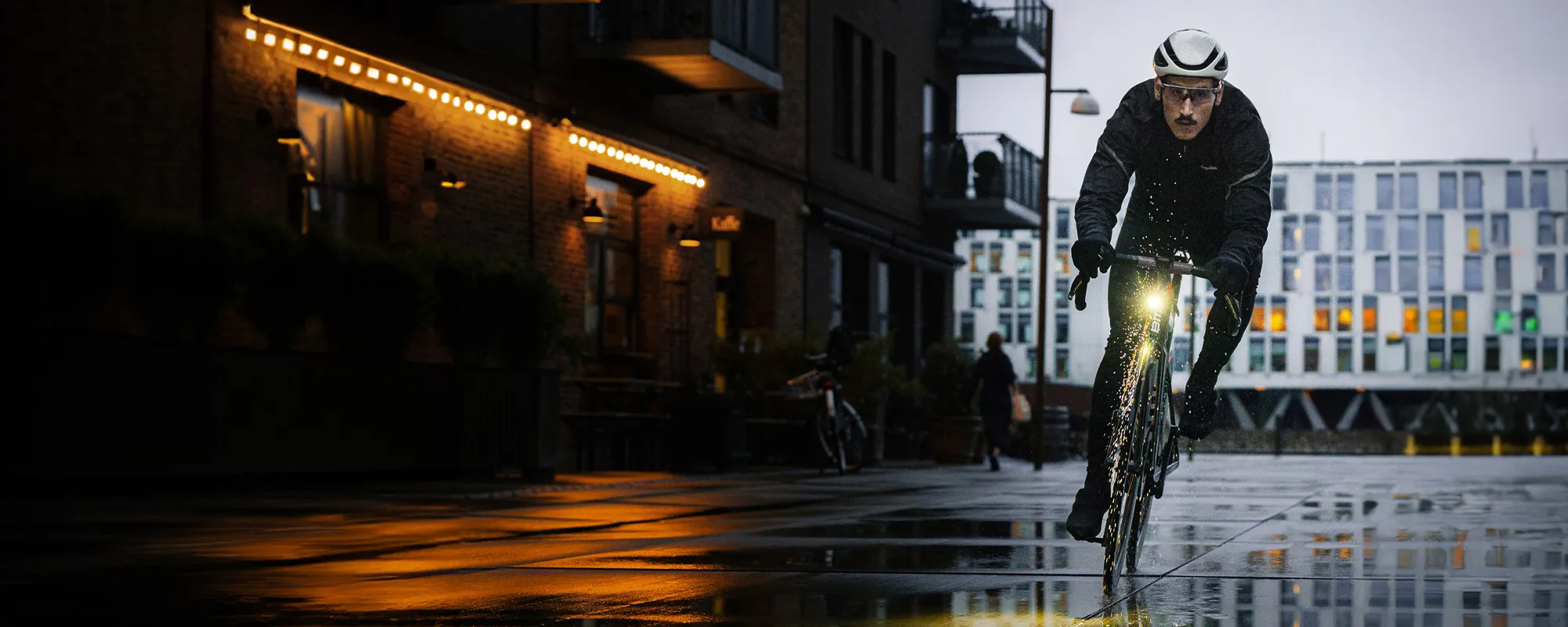 road cyclist riding on a dark wet day in the city with lights