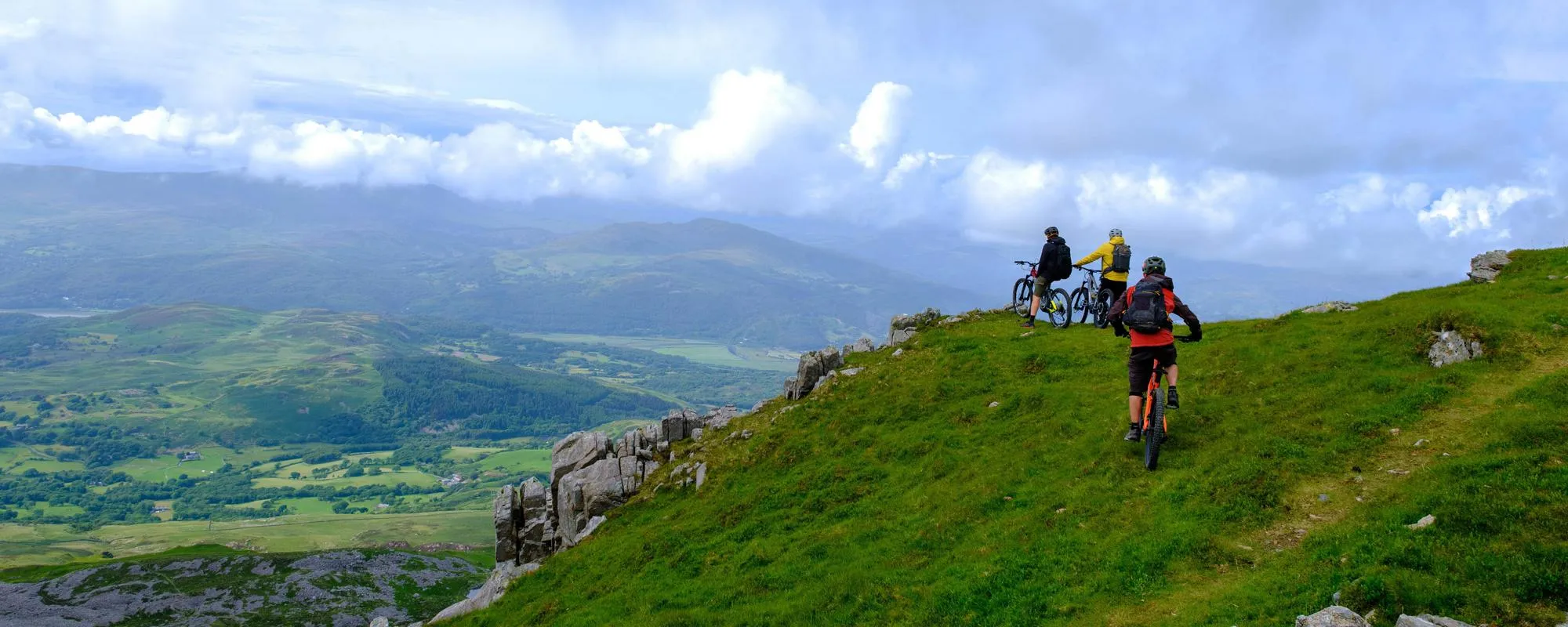 Three mountain bike riders looking at the view from a Welsh mountain