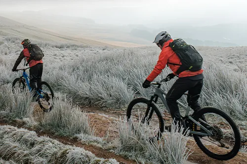 mountain bikers riding e-bikes in the hills on a crisp frosty day with mist  