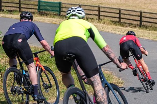 three road cyclists cornering quickly on a sunny day