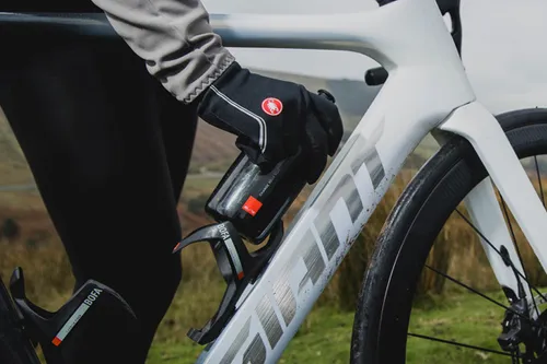 cyclist wearing castelli gloves putting water bottle in cage