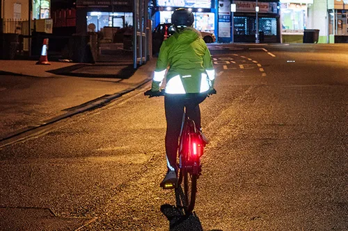 Cyclist riding on a city  street at night with lights, hi-vis and reflective jacket