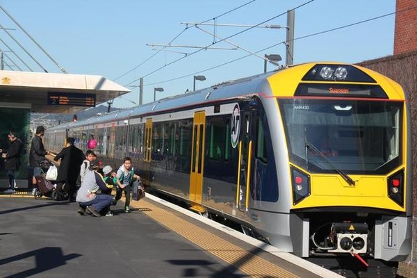 A photo of a train stopped at the platform with passengers boarding.