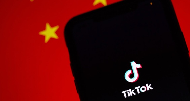 Die Tiktok-App auf einem iPhone. Im Hintergrund ist die chinesische Flagge zu sehen. Foto: Solen Feyissa/Unsplash