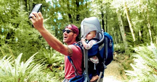 Ein Mann fotografiert sich und sein Kind mit dem Smartphone. Foto: Grover