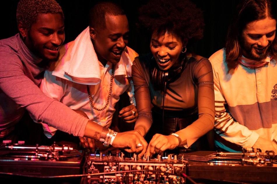Group photo of four people playing with a turntable