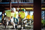 Crew of JB STEEL workers pouring and smoothing concrete at a job site