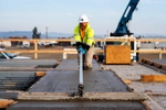 Construction worker at a job site smoothing out a slab of freshly poured concrete