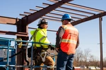 JB STEEL workers wearing safety gear talking on job site 