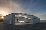 Airplane hanger at sunset with lights on inside and a private plane. 