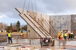 JB STEEL workers lifting concrete wall into place with a crane and chains