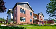 Metal and brick elementary school building with dark green lawn out front