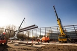 2 cranes lifting steel building sections 