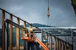 Two construction workers on a scissor-lift bolting two steel beams together