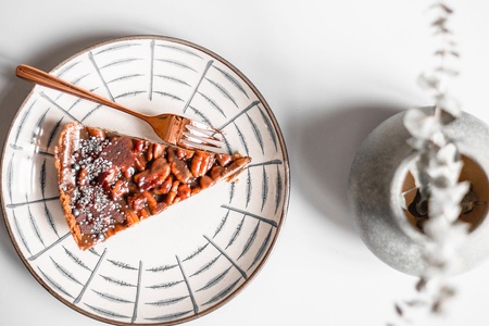 A slice of Vegan Pies Berlin's pecan pie on a plate with a fork next to it