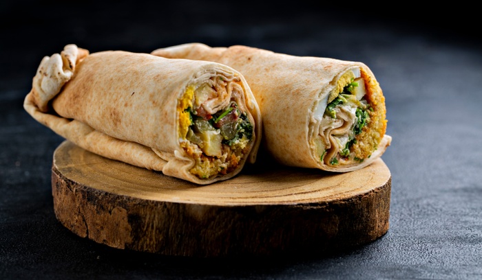 Wrap med hummus, picklad saltgurka, skivad rödlök, strimlad vitkål, vitlök- & harissayoghurt och krispig falafel.
