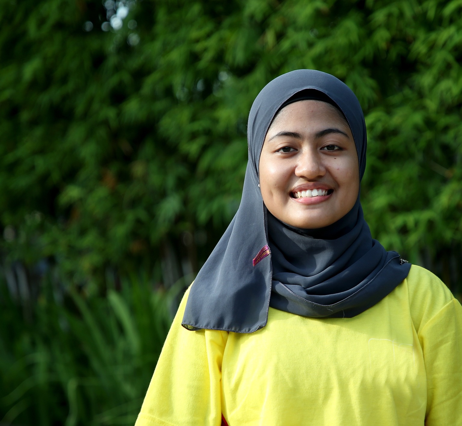 Woman with niqab smiling in front of trees