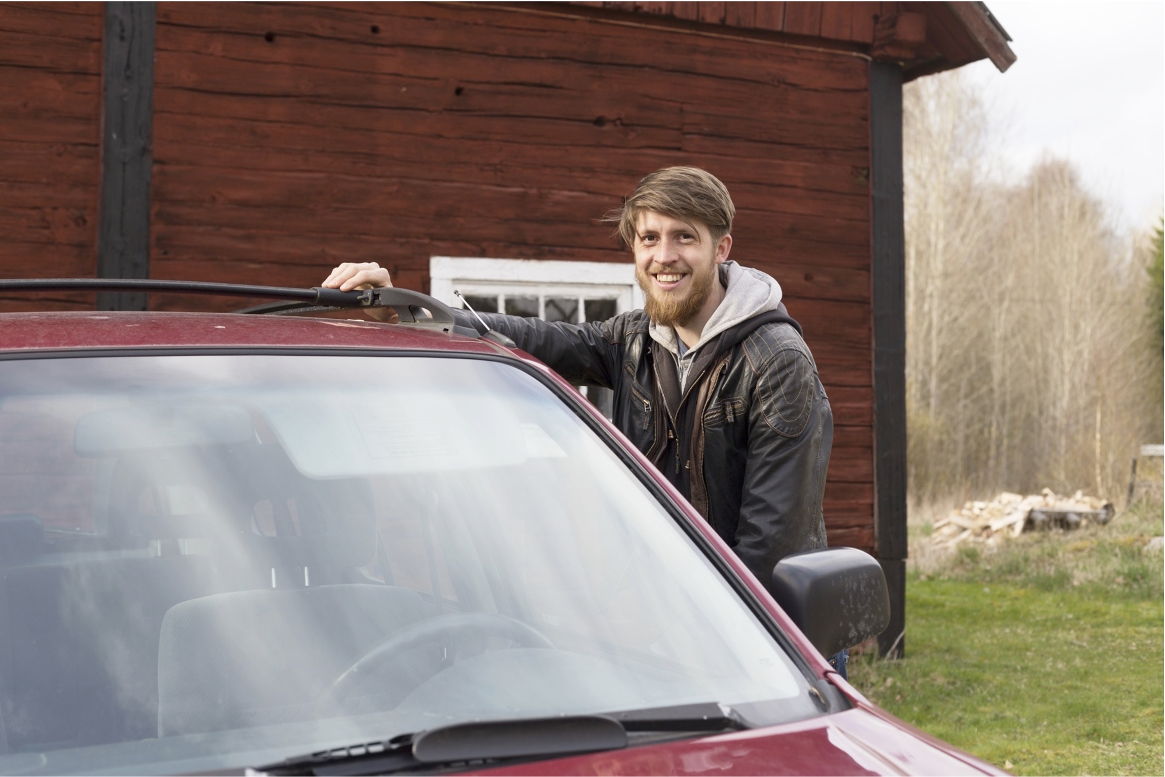 Smiling man standing behind a car