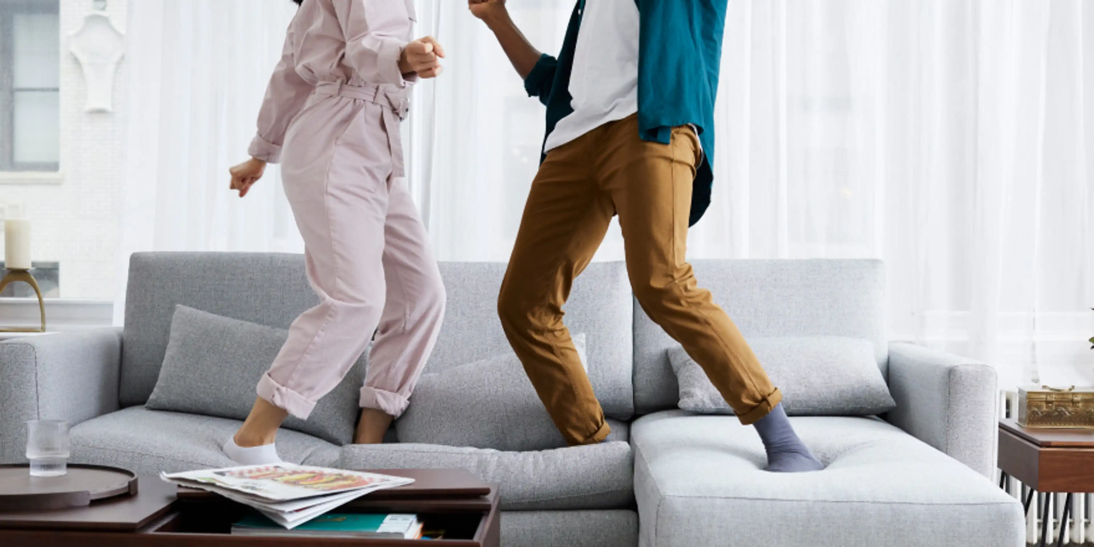 Man and woman dancing on Nomad Sofa in Stone Gray