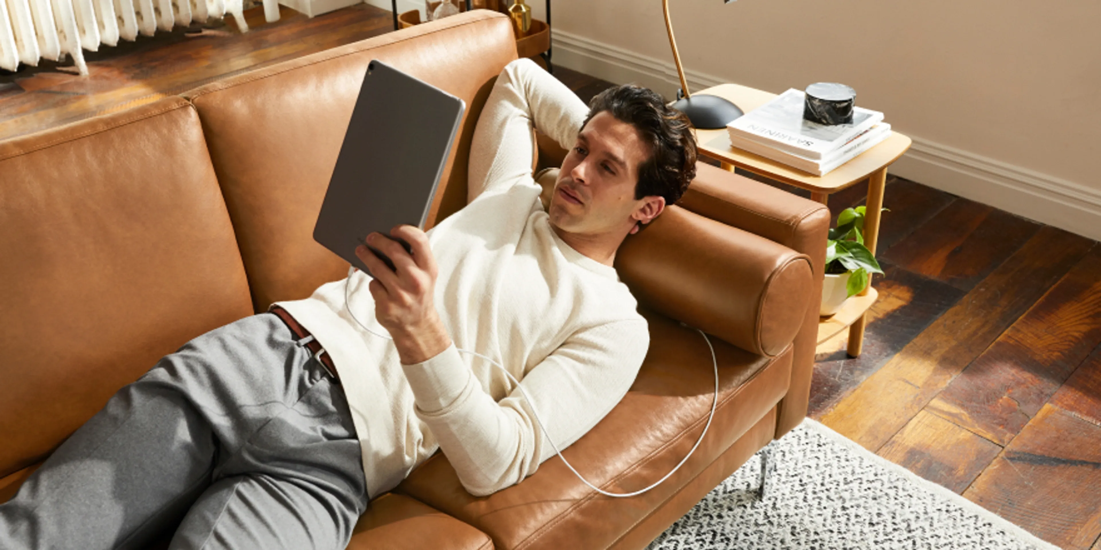 Man relaxing and reading on Nomad Leather Sofa in Camel