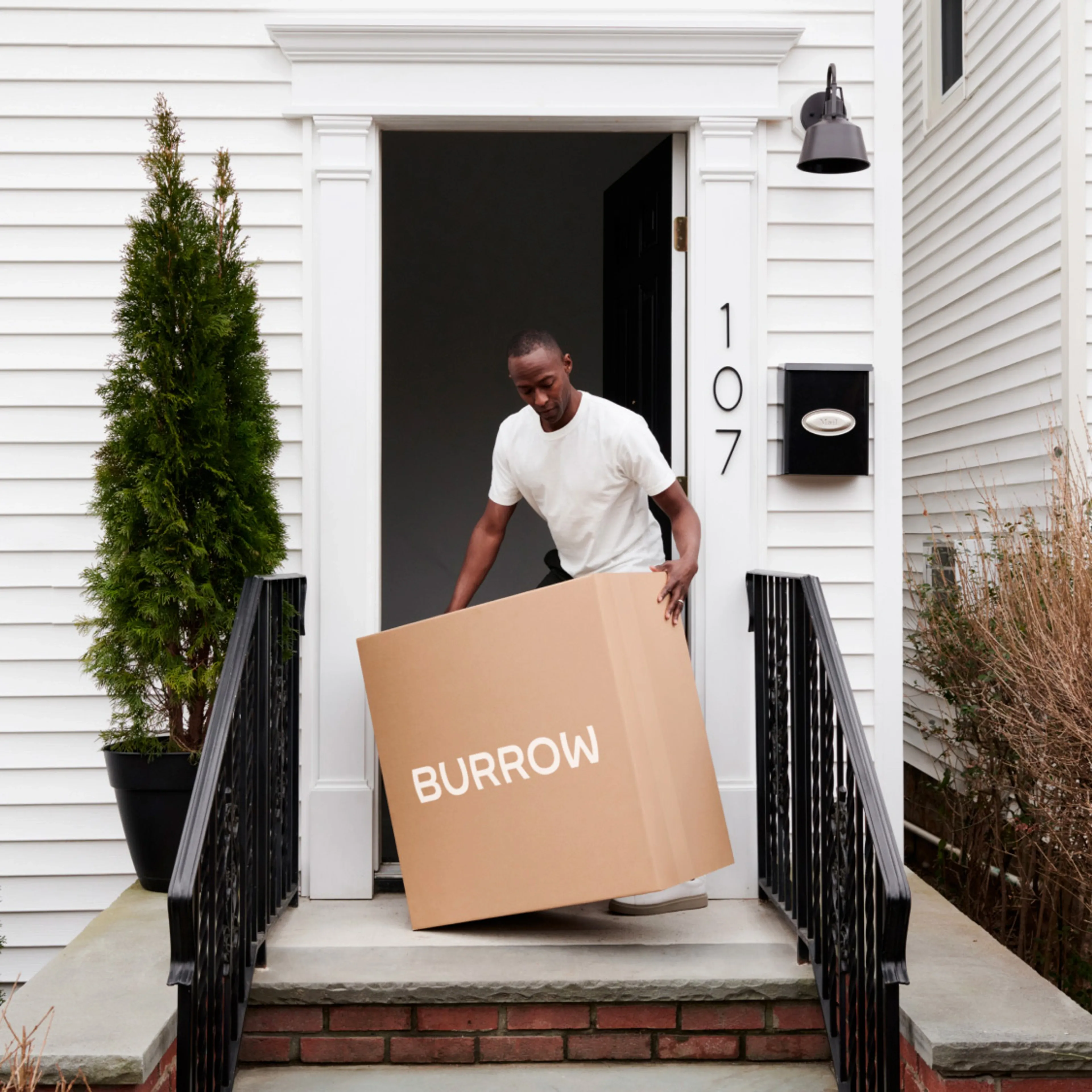 Man moving a Burrow shipping box indoors