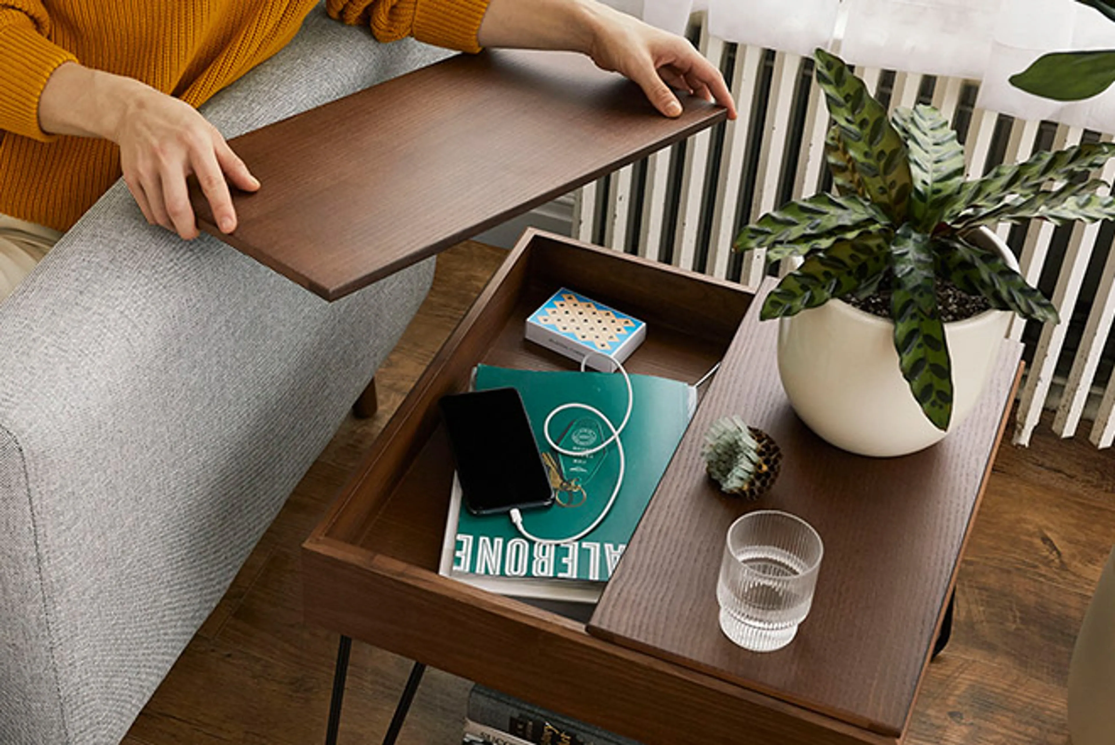 Carta coffee table in walnut showing book and phone inside storage table.