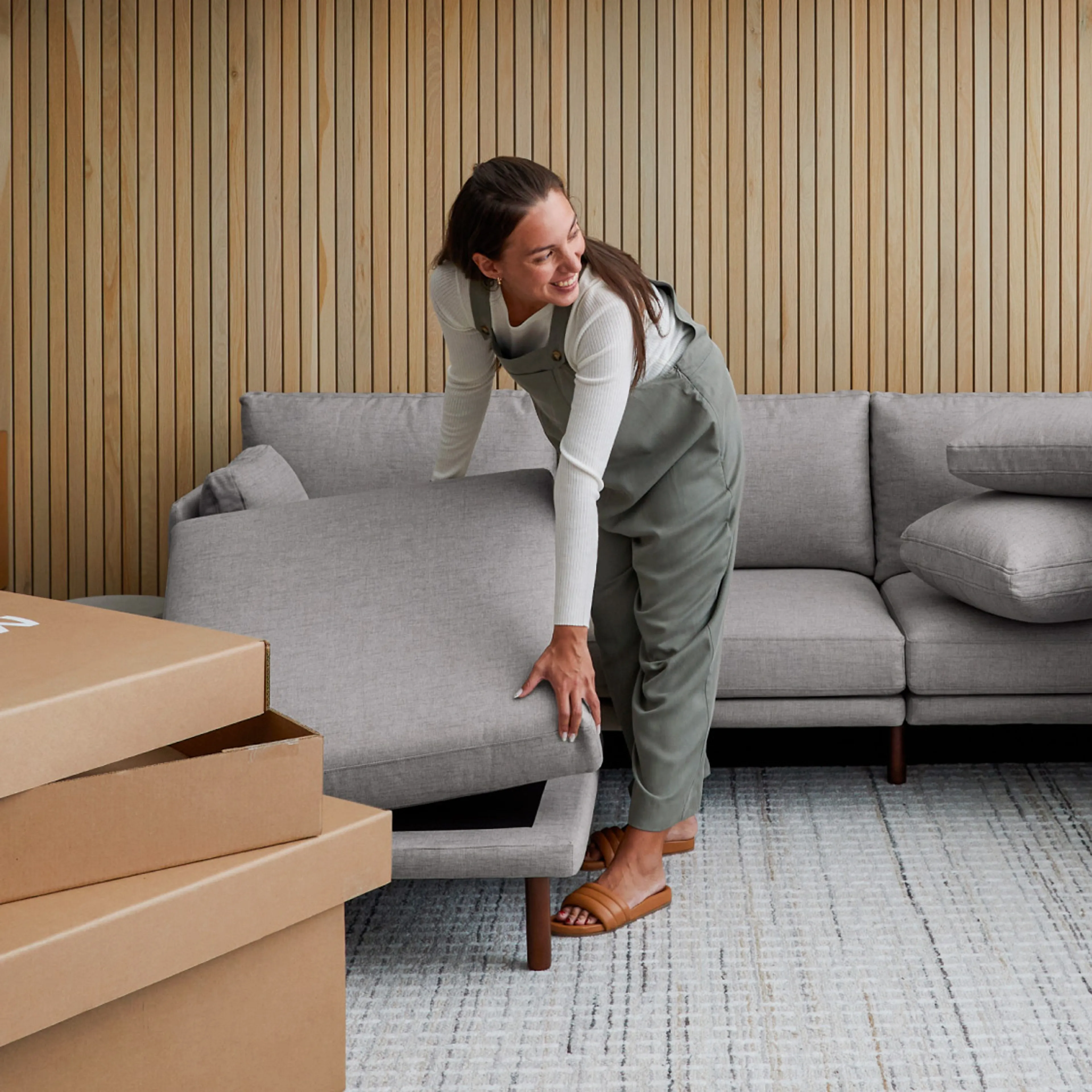 Woman in overalls effortlessly setting up a Field sofa