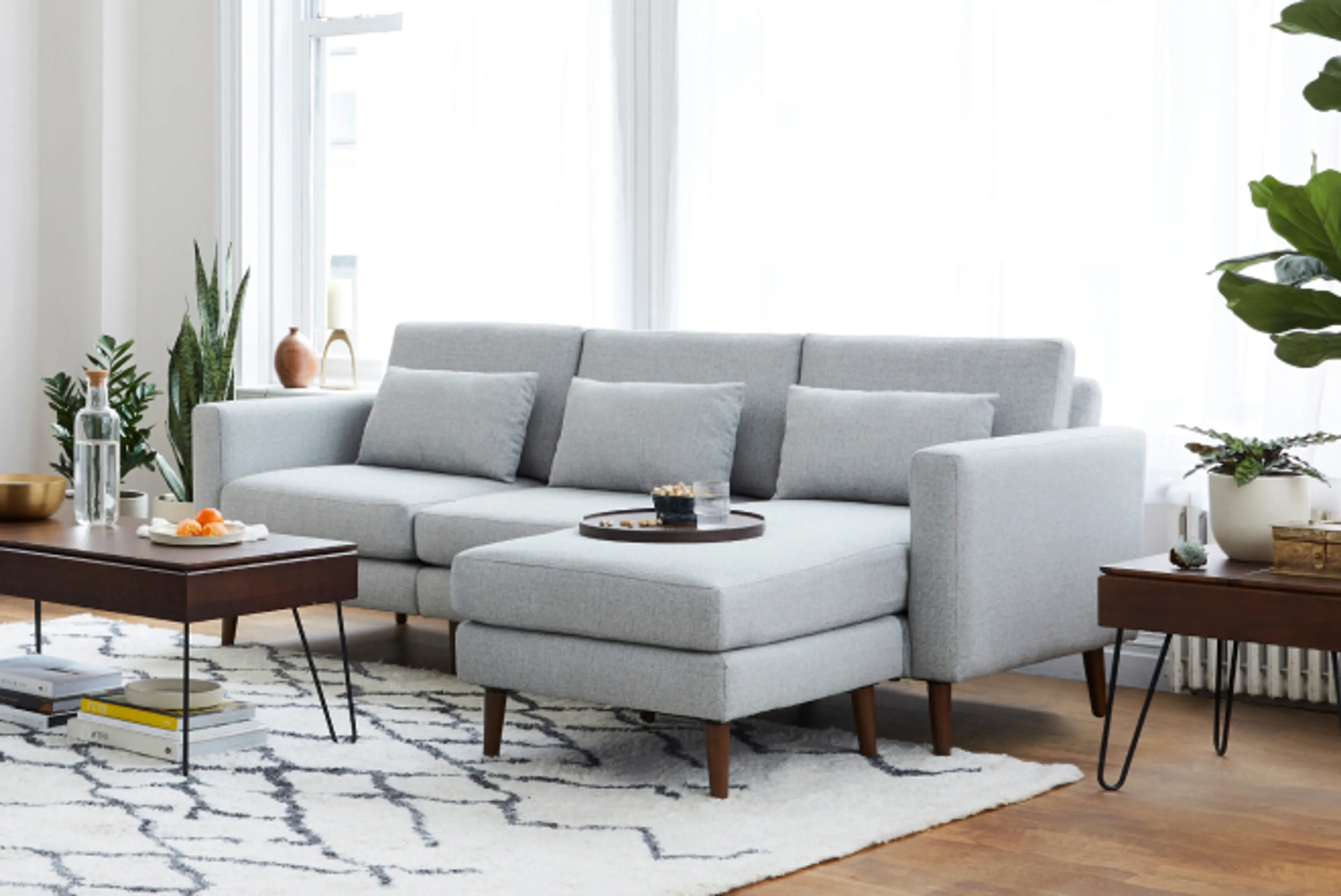 Gray nomad sofa sectional in living room setting with rug, coffee and side table