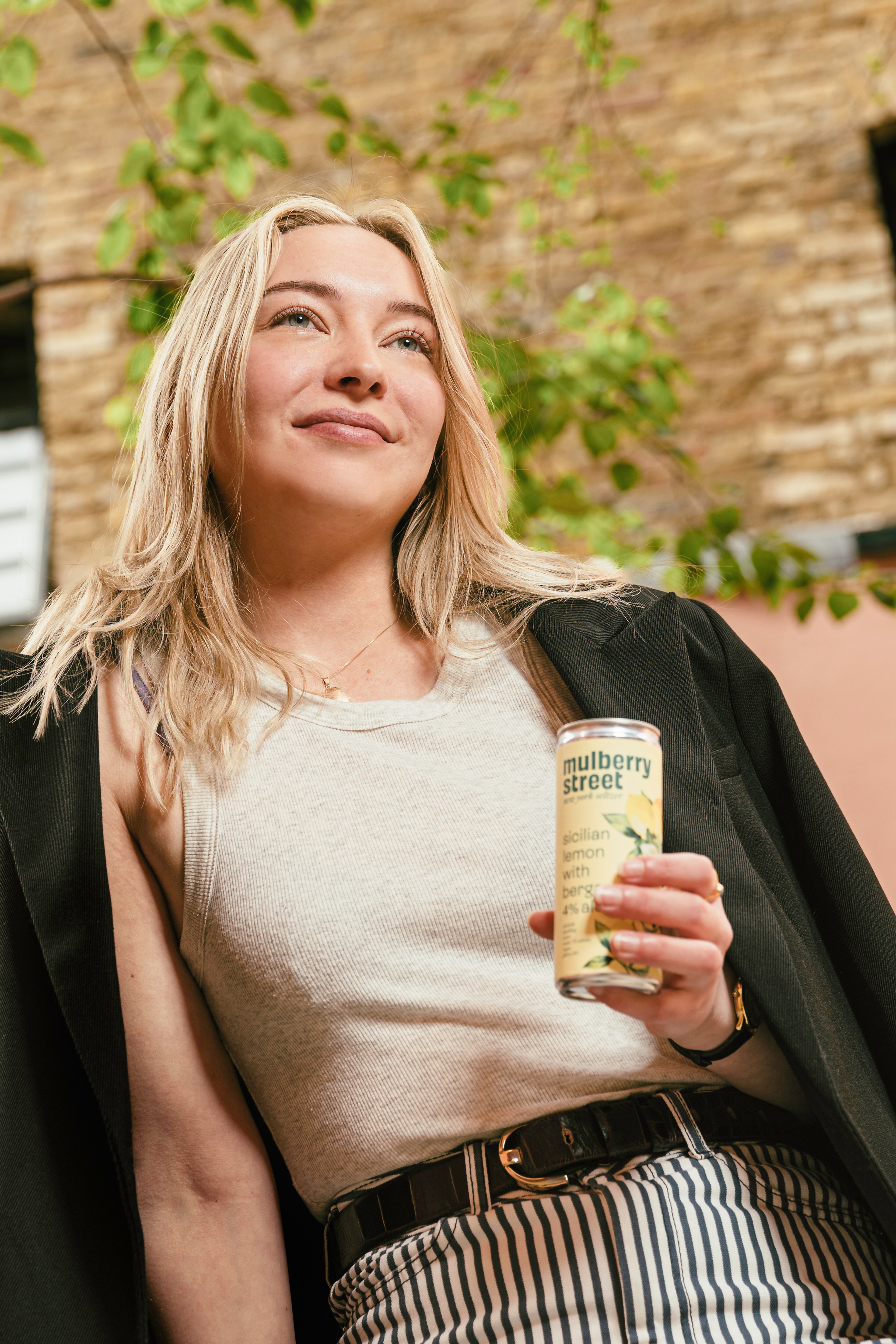 A person holding a can of Mulberry Street Lemon Seltzer