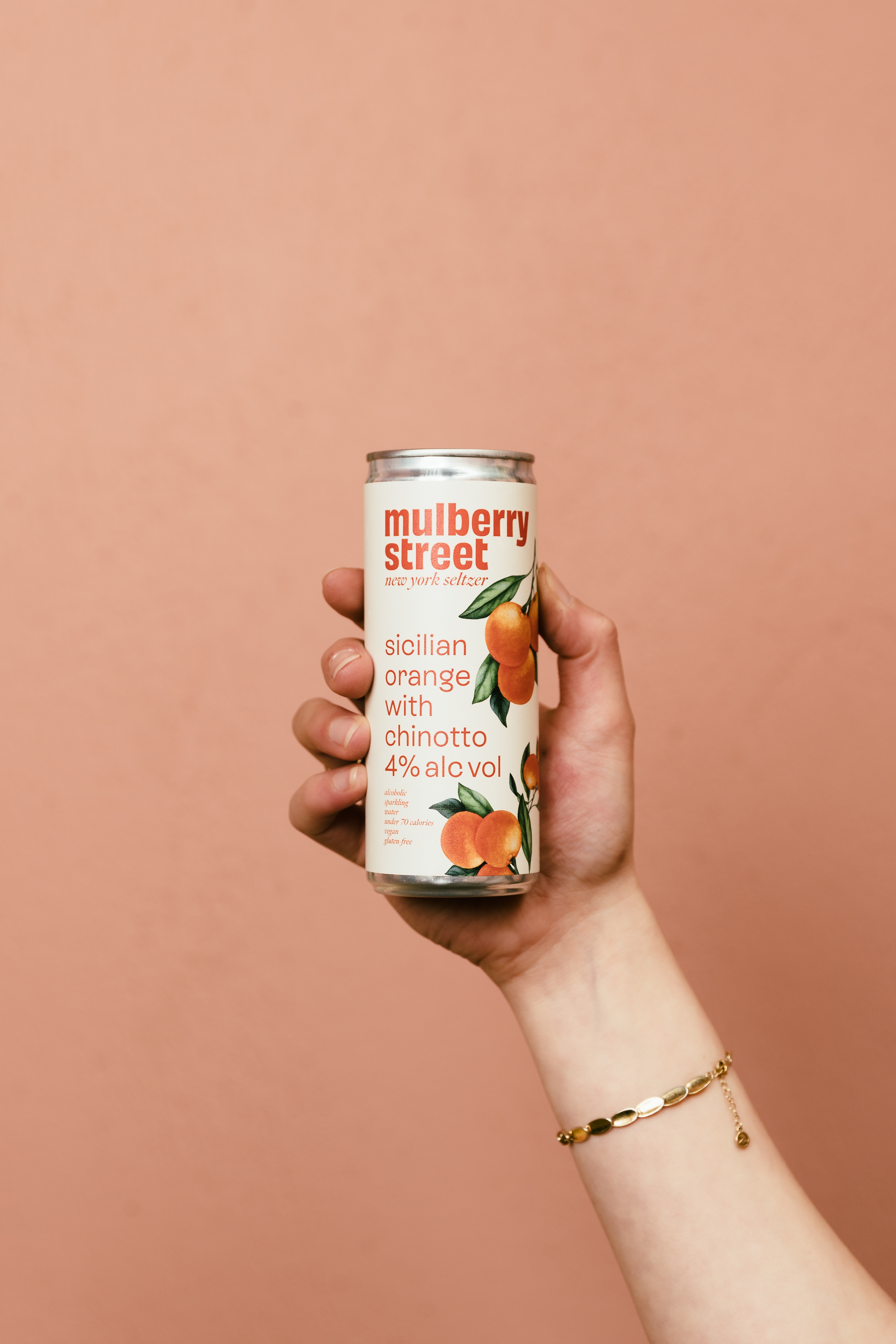 A hand holding a can of Mulberry Street Orange Seltzer