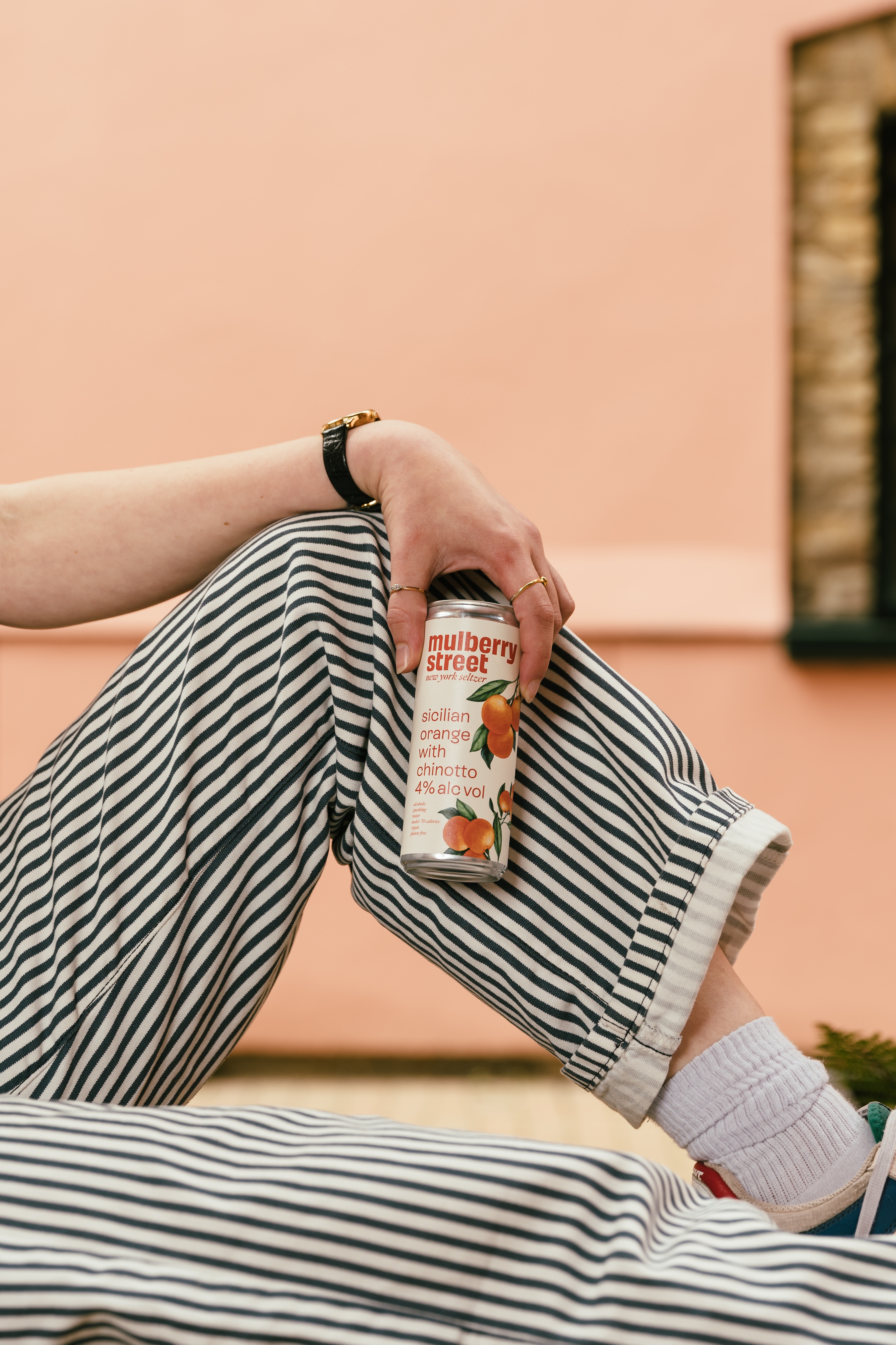 A person holding a can of Mulberry Street Orange Seltzer