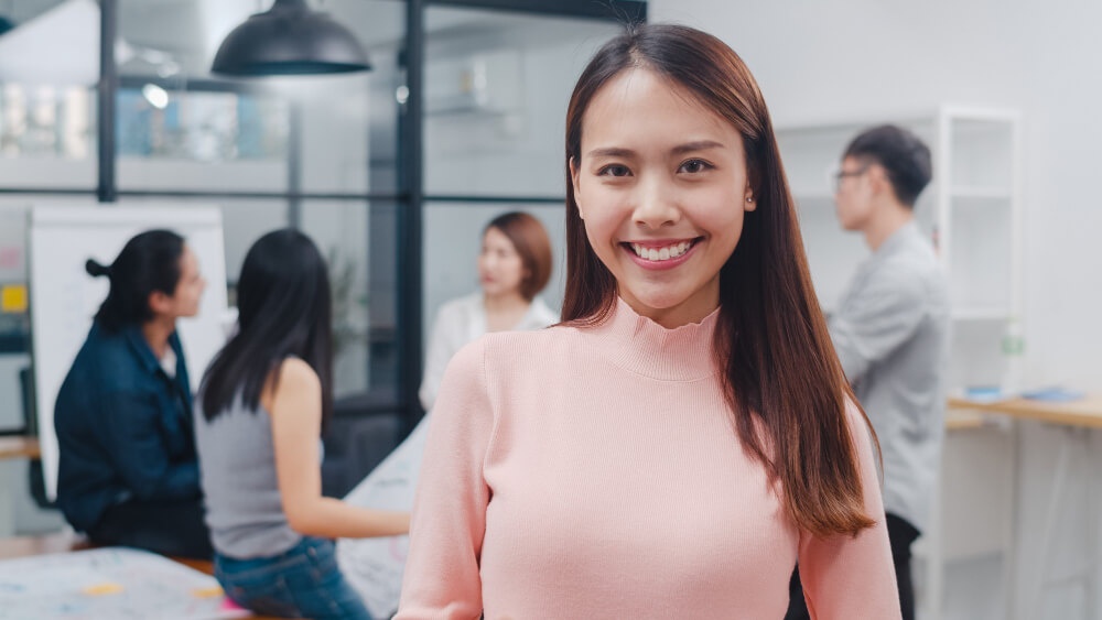 Seorang wanita senyum dalam persekitaran kerja pejabat. 