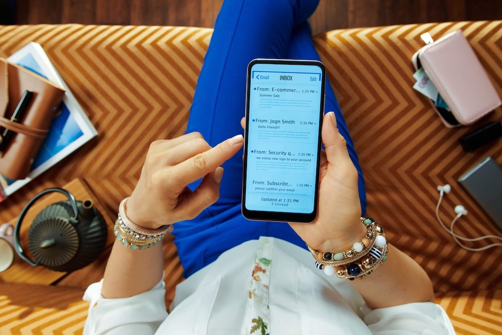 Seorang individu sedang melihat email di telefon bimbit.