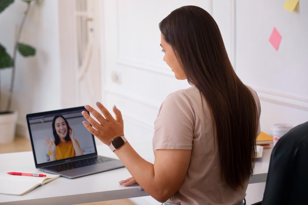 Dua orang wanita tengah menjalani temu duga online di sebuah bilik cerah. 