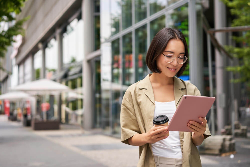 membaca-dari-tablet.jpgSeorang wanita membaca maklumat dalam tablet di luar sebuah bangunan sambil memegang secawan minuman 