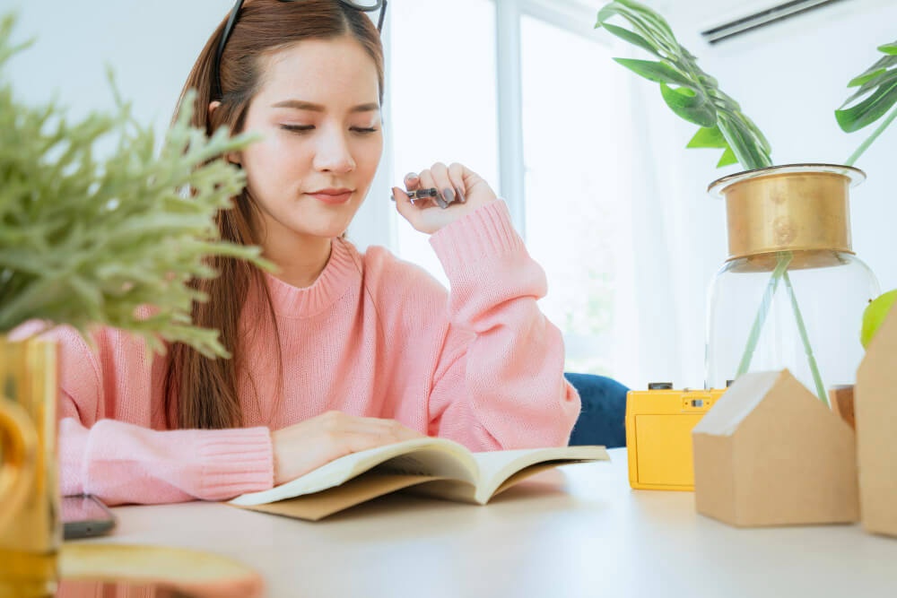 Seorang gadis sedang membaca buku di ruang cerah.