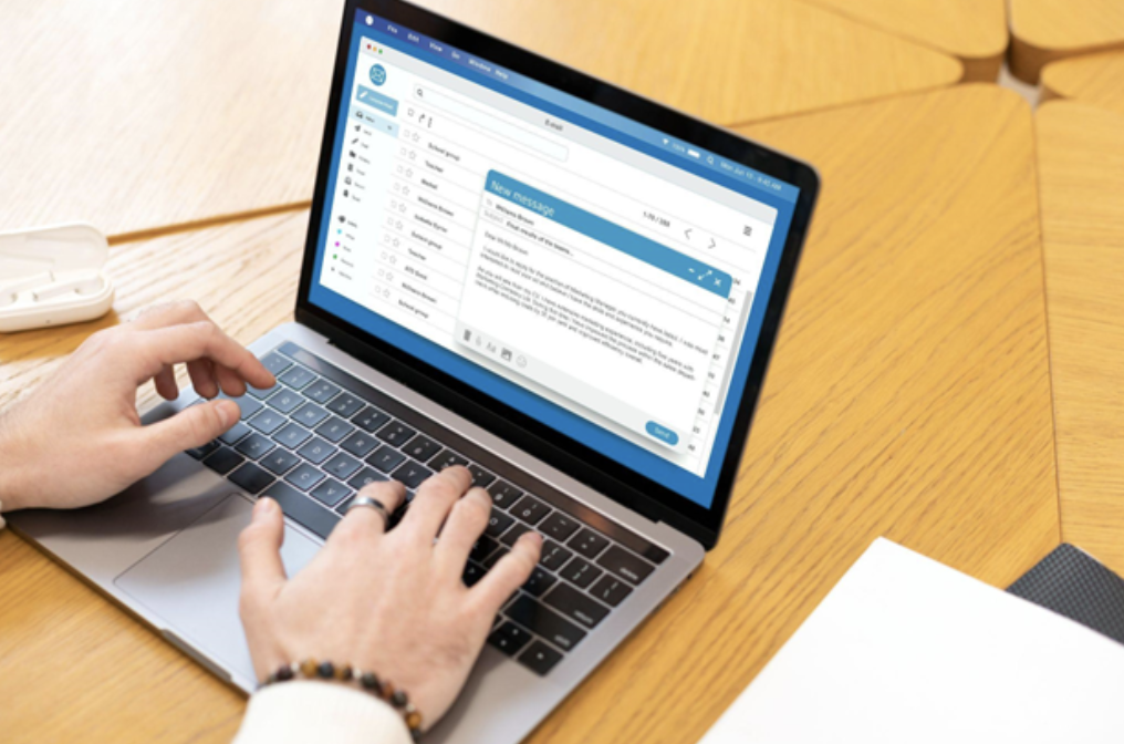 Man’s hands typing an email on an open laptop