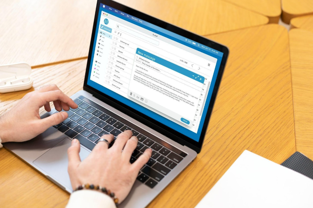 Man's hands typing an email on open laptop