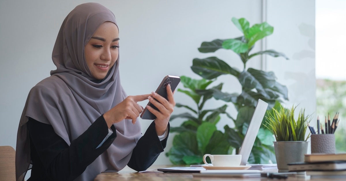 Business casual muslim woman on her phone at her desk