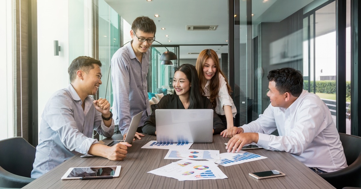 Diverse group in the workplace reviewing graphs in a meeting